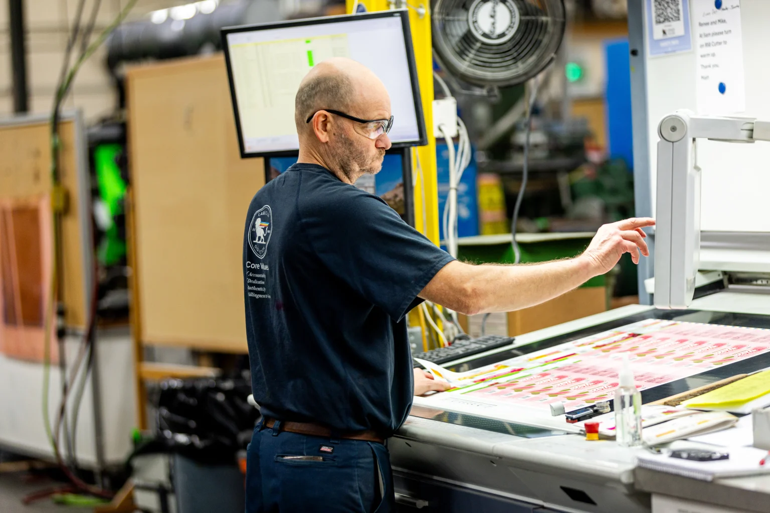 An Epsen Hillmer employee uses new technology to color correct and QA a sheet of product labels.